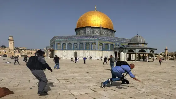 A camera operator falls as an Israeli police officer runs after him during clashes with Palestinians at the compound that houses Al-Aqsa Mosque, known to Muslims as Noble Sanctuary and to Jews as Temple Mount, in Jerusalem's Old City, May 10, 2021. REUTERS/Ammar Awad TPX IMAGES OF THE DAY