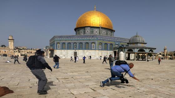 A camera operator falls as an Israeli police officer runs after him during clashes with Palestinians at the compound that houses Al-Aqsa Mosque, known to Muslims as Noble Sanctuary and to Jews as Temple Mount, in Jerusalem's Old City, May 10, 2021. REUTERS/Ammar Awad TPX IMAGES OF THE DAY